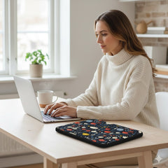 Woman using a laptop on a wooden table with a Scandinavian floral laptop sleeve by Drese Art